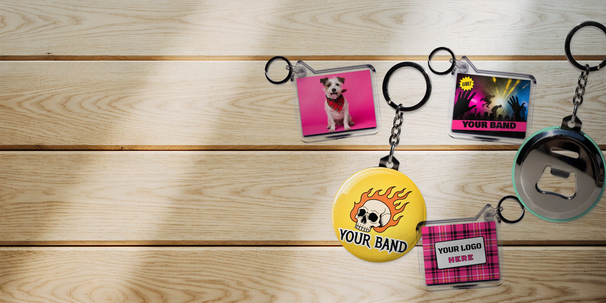 Custom clear photo keyrings and bottle opener keyrings with punk band designs and a dog photo on a sunlit oak table