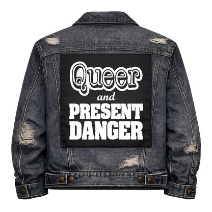 Black fabric back patch sew onto a denim jacket with the design "Queer and Present Danger"