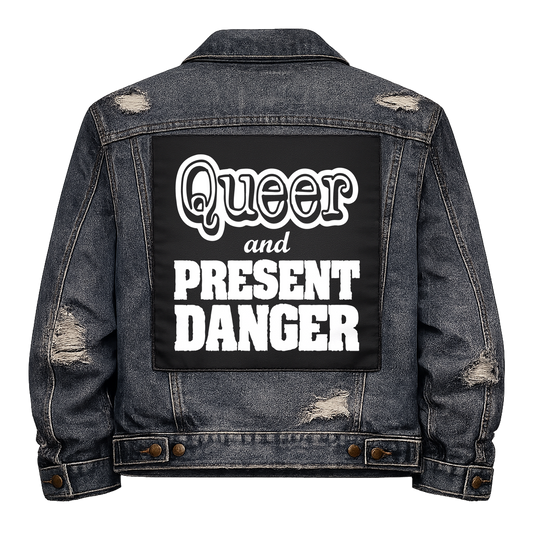 Black fabric back patch sew onto a denim jacket with the design "Queer and Present Danger"